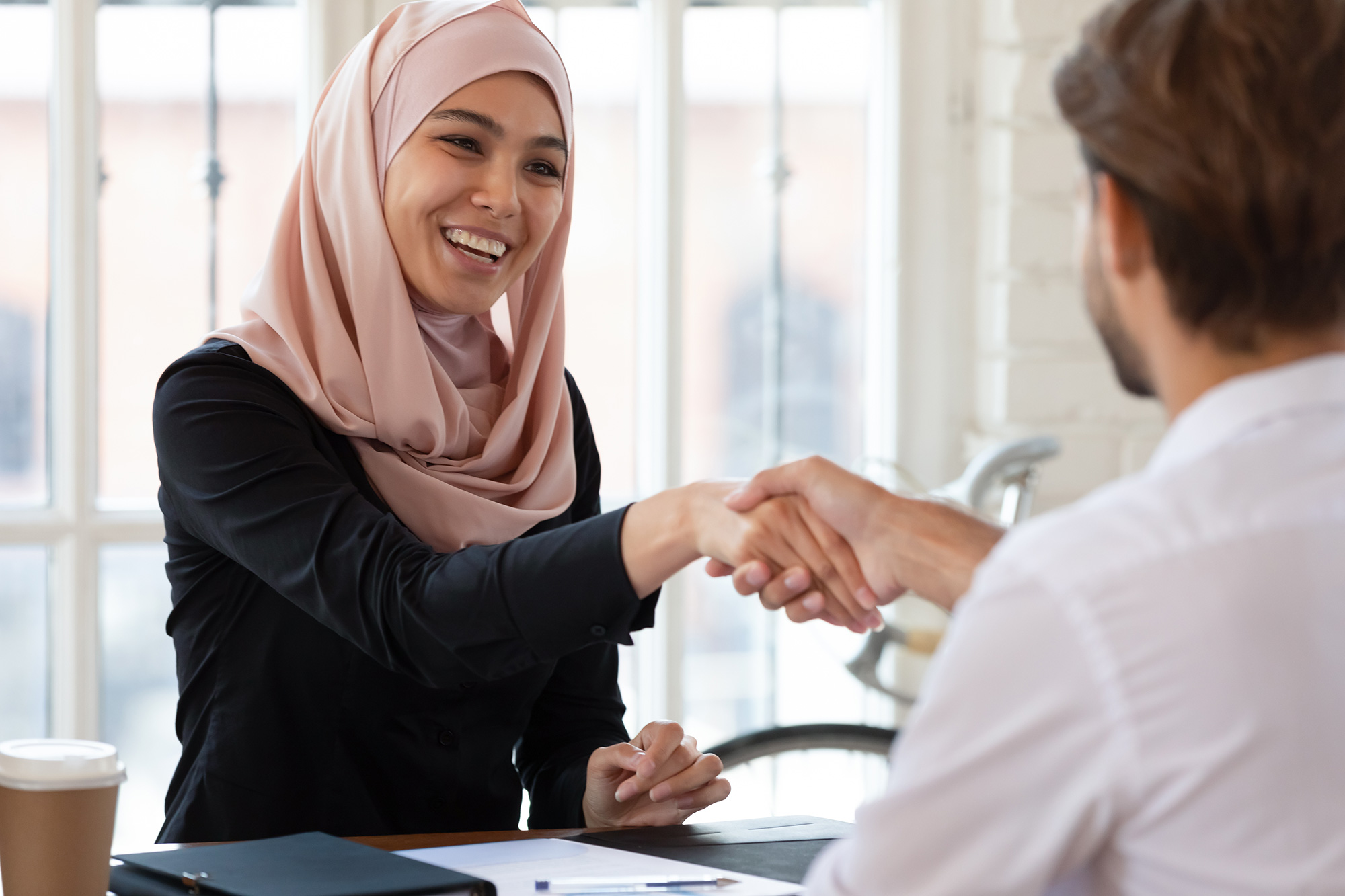 Two people in an office shaking hands as if in an interview