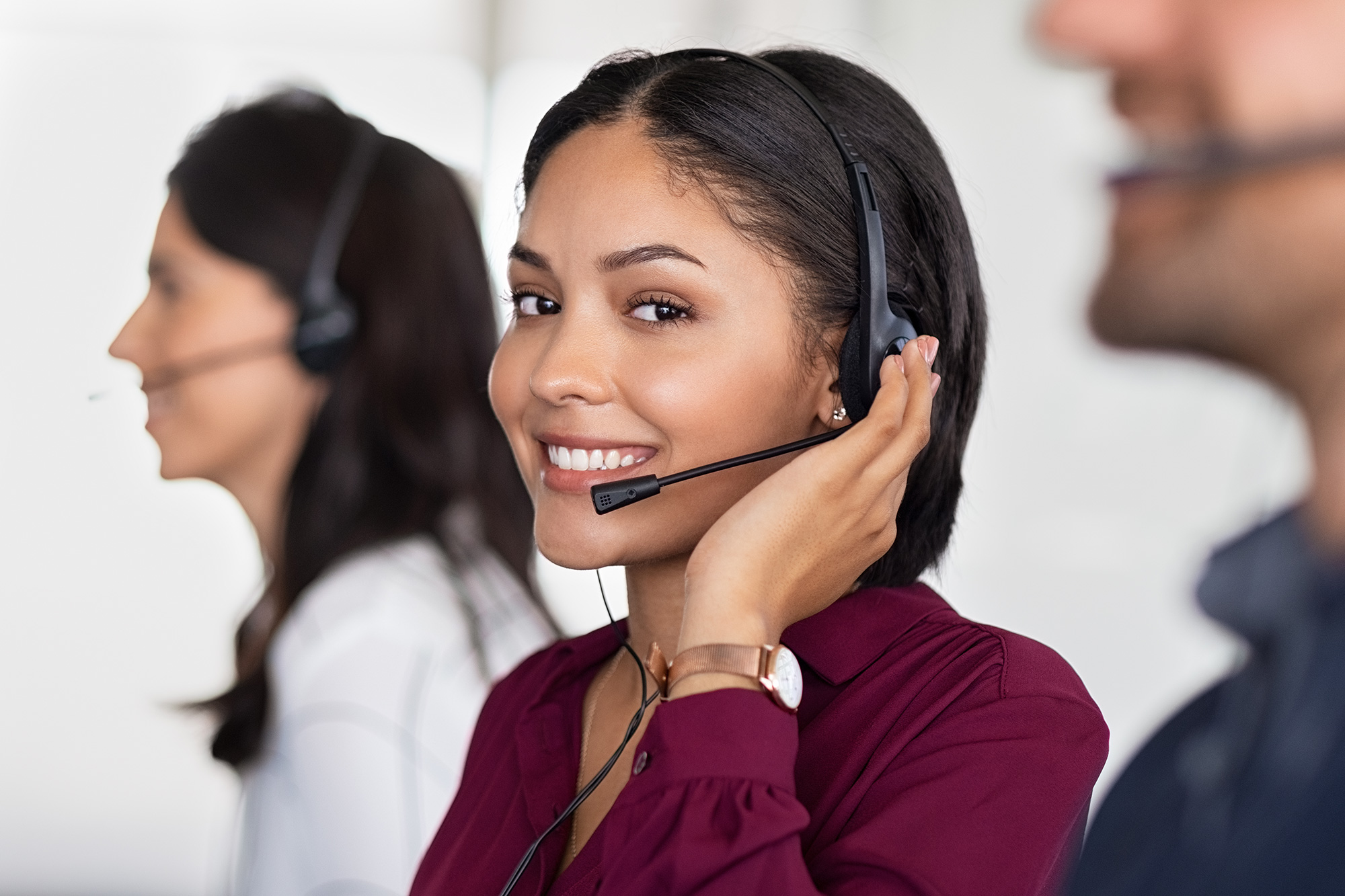 Una representante de servicio al cliente con auriculares ve a la cámara y sonríe.