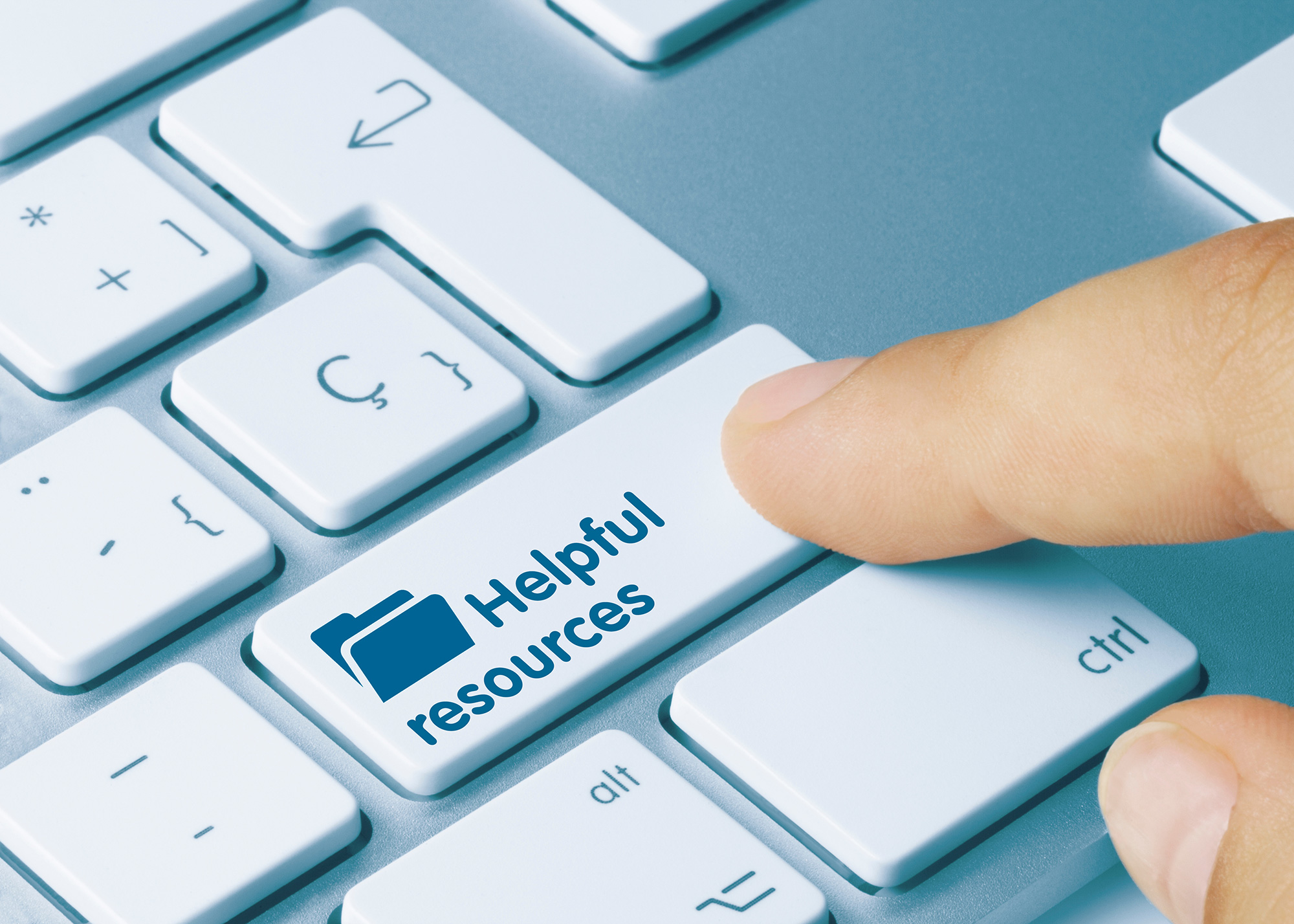 Close-up of a finger pressing a key on a laptop keyboard. The key reads “Helpful Resources.”