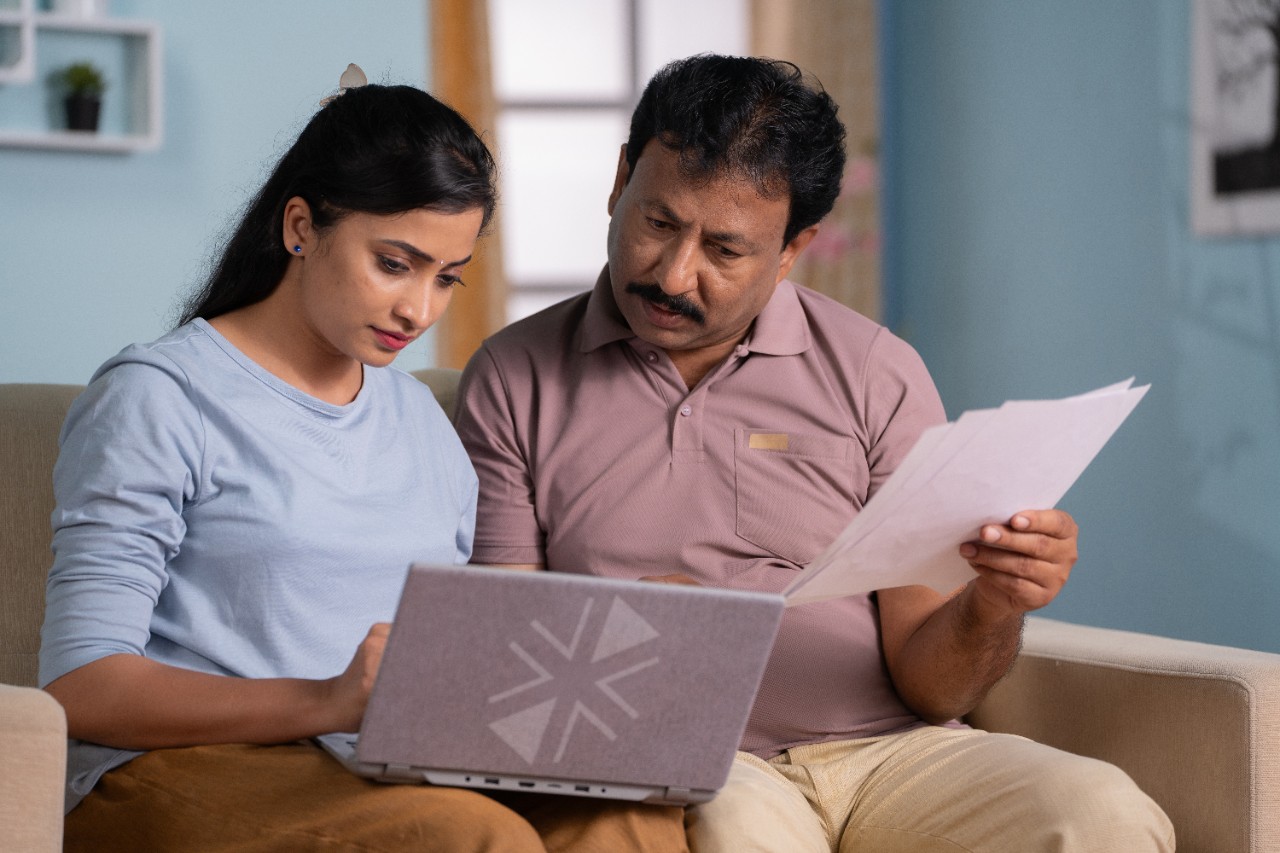 Indian father with daughter discussing by checking documents on laptop at home - concept of Parental Guidance, Financial Planning and relationship bonding.